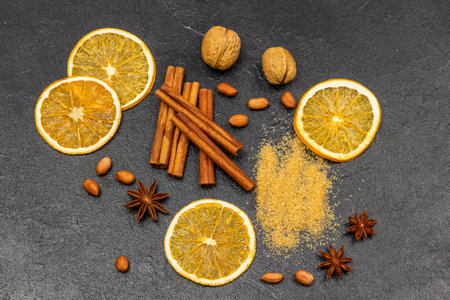 Brown sugar, cinnamon sticks, orange chips and star anise. flat lay. black backgroundの写真素材