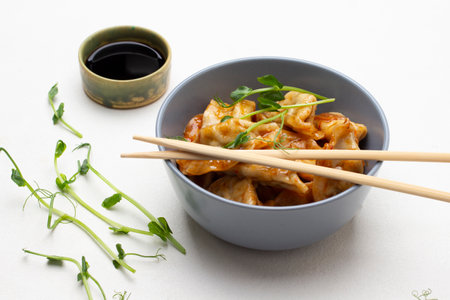 Pea microgreens on table. Gyoza dumplings and chopsticks in gray bowl. Soy sauce in bowl. top view. white backgroundの写真素材