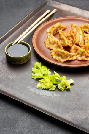 Gyoza dumplings on ceramic plate on rusty tray. Soy sauce in bowl and chopsticks. top view. black backgroundの写真素材
