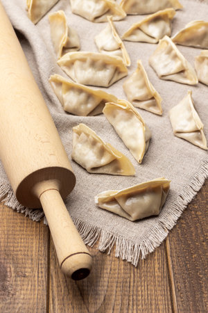 Rolling pin and raw gyoza dumplings on linen napkin. top view. wooden backgroundの写真素材