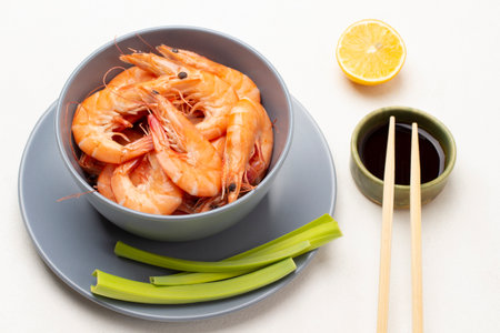 Chopsticks and soy sauce in a bowl. Shrimps in gray bowl and celery stalks on plate. top view. white backgroundの写真素材