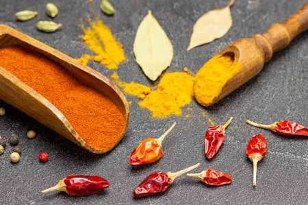 Ground pepper and turmeric in wooden scoops. Pods of dry red pepper on table. top view. black backgroundの写真素材