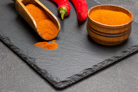 Ground paprika in bowl and scoop. Fresh red pepper on stone board. top view. black backgroundの写真素材