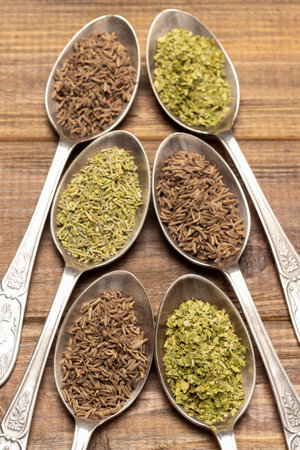 Dry herbs and fennel seeds in metal spoons. top view. wooden backgroundの写真素材