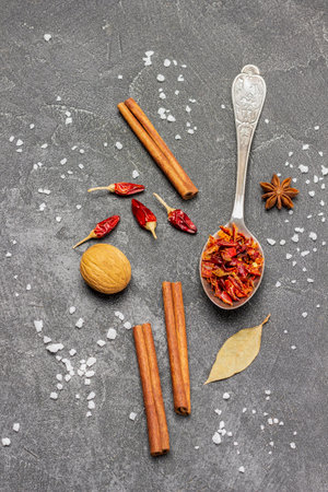 Dry peppers in metal spoon, pepper pods and cinnamon sticks on table. copyspace. flat lay. black backgroundの写真素材