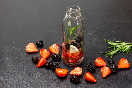 Strawberries and blackberries on the table. A bottle of water with berries. copyspace. Black background.の写真素材