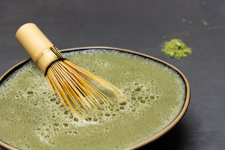 Bamboo whisk in a black bowl with matcha green tea. black backgroundの写真素材