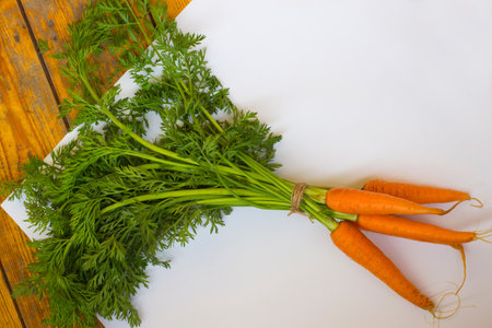 Bundle of carrots on a white and wooden background. top viewの写真素材