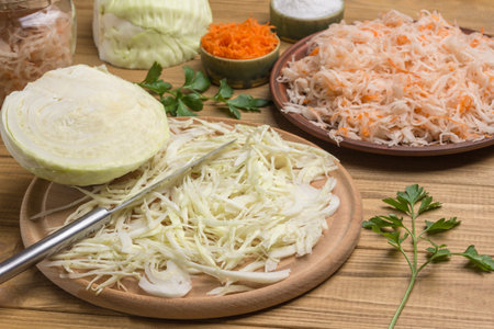 Sauerkraut in plate, Sliced raw cabbage, knife on cutting board, half cabbage head. Homemade Fermentation Products. Close upの写真素材