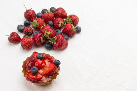 Tart decorated with fresh berries. Strawberry and blueberries on white background. Flat lay Copy space.の写真素材