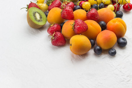 Assorted fresh berries and fruits. Apricots Kiwi Strawberry Cherry Blueberry on white background....