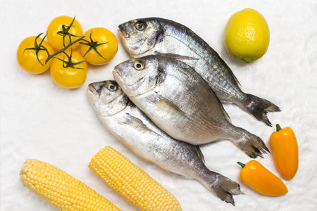 Raw fish with yellow vegetables. White background. Flat lay.の写真素材