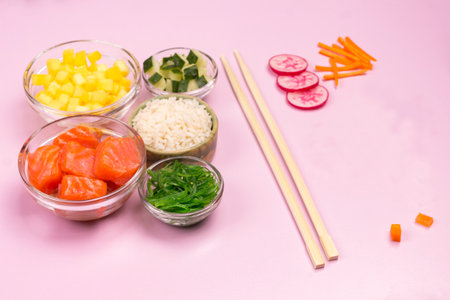 Set of raw vegetables, red fish, rice, soy sauce in glass bowls. Hawaiian dish Bamboo chopsticks on pink background. Top viewの写真素材