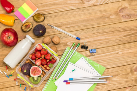 Nutritious lunch box made of fruits, berries and nuts. Bottle of water yogurt. Light wooden desk. Flat lay. Copy spaceの写真素材