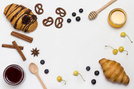 Croissants and figured cookies, berries, apricots honey, jam, cinnamon. Set of products for nutritious breakfast. White background. Flat lay, copy spaceの写真素材