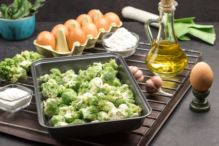 Mix broccoli and Brussels sprouts in food metal pallet. Eggs, garlic and onions, flour and butter in bottle on metal grill. Cooking casseroles. Black background.の写真素材