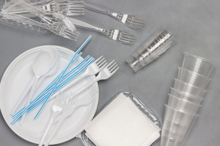 Disposable white plastic tableware. Plate, spoons, forks, straws for drinks. Plastic processing...
