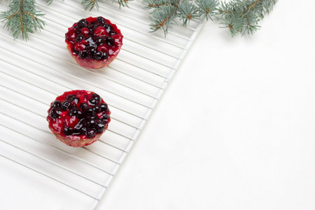 Berry muffins on white lattice. Cranberries on table. Fir branches. Copy space. White Background. Top viewの写真素材