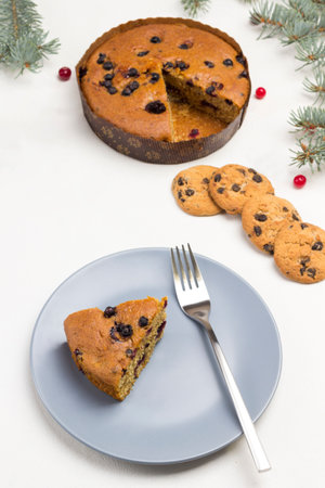 Piece of pie and fork on gray plate. Raisin pie and cookies on the table. Fir branches. White Background. Top viewの写真素材