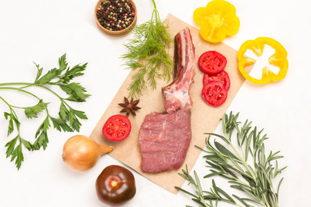 Veal meat with bone on paper. Colored chopped peppers. Sprigs of rosemary and parsley. Balanced food set. White background. Flat layの写真素材