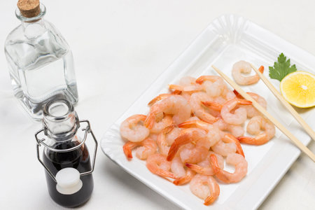 Shrimps with lemon on white plate. Soy sauce and water in glass bottles. White background. Top viewの写真素材
