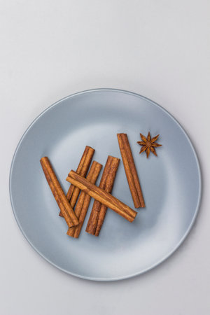 Cinnamon sticks and star anise in gray ceramic plate. Gray background. Flat lay. Copy space.の写真素材