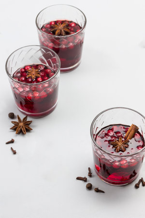 Hot winter drink with cranberries and spices. Star anise, cloves, pieces of brown sugar on table. Gray background. Top view.の写真素材