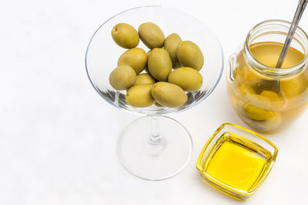Green olive on slice of bread. Jar of olives. Oil bottle White background. Top viewの写真素材
