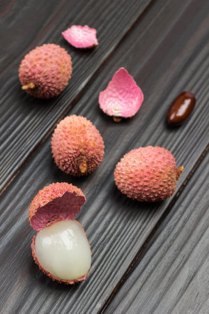 Lychee berries on dark wooden background. Top view.