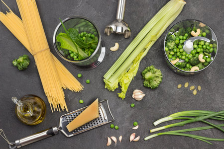 Set of vegetables on table and in blender bowl. Pasta and Parmesan cheese on grater. Black background. Flat layの写真素材