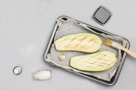 Eggplant halves on pallet. Whole eggplant, salt and sauce on table. Gray background. Flat lay. Copy spaceの写真素材