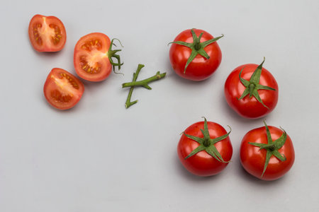 Whole tomato, chopped tomato wedges and scissors. Gray background. Top viewの写真素材