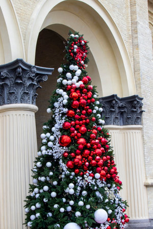 New Year tree under the arch of the building. Red and white balls on the tree.の写真素材