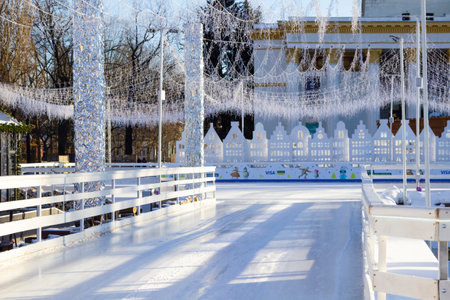 A skating rink decorated with festive illuminations. An ice track and fences around it.の写真素材