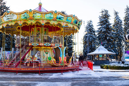 Children's carousel in the city park. Lighting garlands on the trees. Snow on the ground.の写真素材