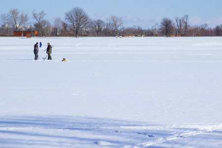 A frozen river in winter. In the distance, two fishermen stand on the ice.の写真素材