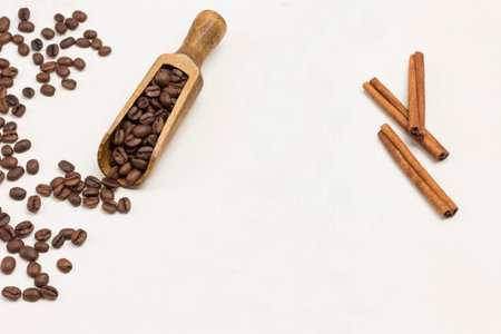 Grains of coffee in wooden scoop and on the table. White background. Top view