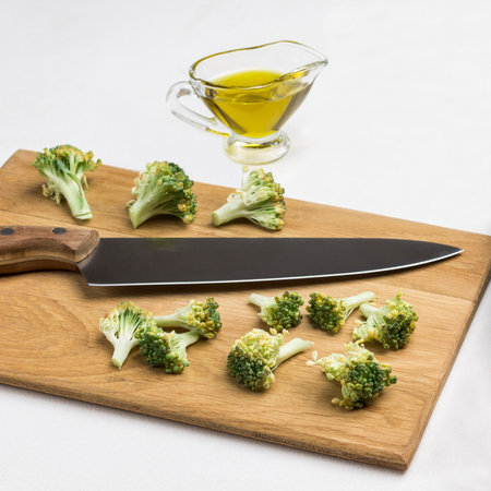 Kitchen knife, fresh cabbage and broccoli on cutting board. Olive oil. Salt shaker. White background. Top view.の写真素材