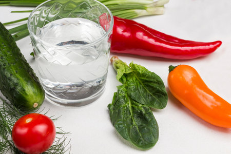 Glass of water, spinach leaves and vegetables. White background. Top viewの写真素材