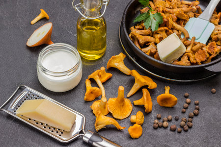 Cheese on grater, chopped onion raw chanterelles on table. Fried chanterelles in pan. Black background. Top viewの写真素材