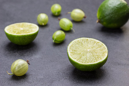 Lime halves and gooseberry berries on black background. Close up. Natural protection against colds.の写真素材