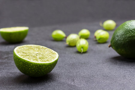 Lime halves and gooseberry berries on black background. Close up. Natural protection against colds.の写真素材