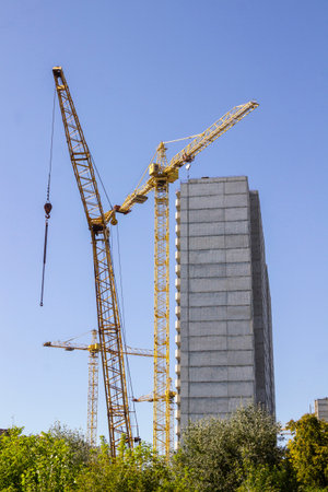 The facade of a house under construction and a construction crane.の写真素材
