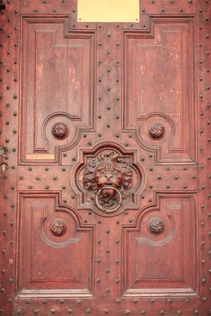 wooden carved door with a handle in the form of a lionâs headの写真素材
