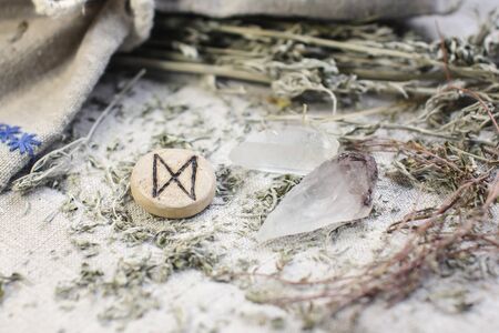 Scandinavian wooden rune Dagaz, Daeg on a rough linen cloth with amethyst crystalline, rock crystal and dried wormwood.の写真素材