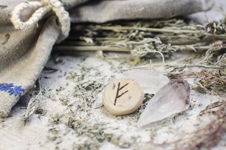 Scandinavian wooden rune Fehu, Fe, Feoh on a rough linen cloth with amethyst crystalline, rock crystal and dried wormwood.の写真素材