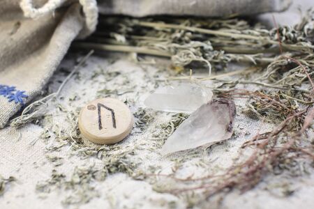 Scandinavian wooden rune Uruz, Ur on a rough linen cloth with amethyst crystalline, rock crystal and dried wormwood.の写真素材