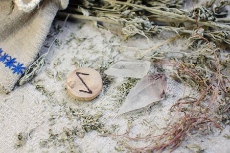 Scandinavian wooden rune Iwaz, Eoh on a rough linen cloth with amethyst crystalline, rock crystal and dried wormwood.の写真素材