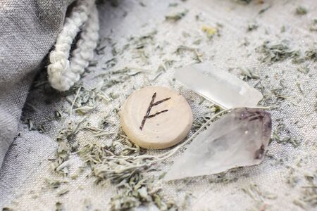 Scandinavian wooden rune Fehu, Fe, Feoh on a rough linen cloth with amethyst crystalline, rock crystal and dried wormwoodの写真素材