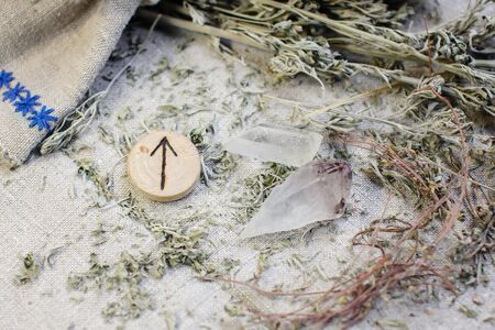 Scandinavian wooden rune Tiwaz, Teiwaz , Tir on a rough linen cloth with amethyst crystalline, rock crystal and dried wormwood.の写真素材